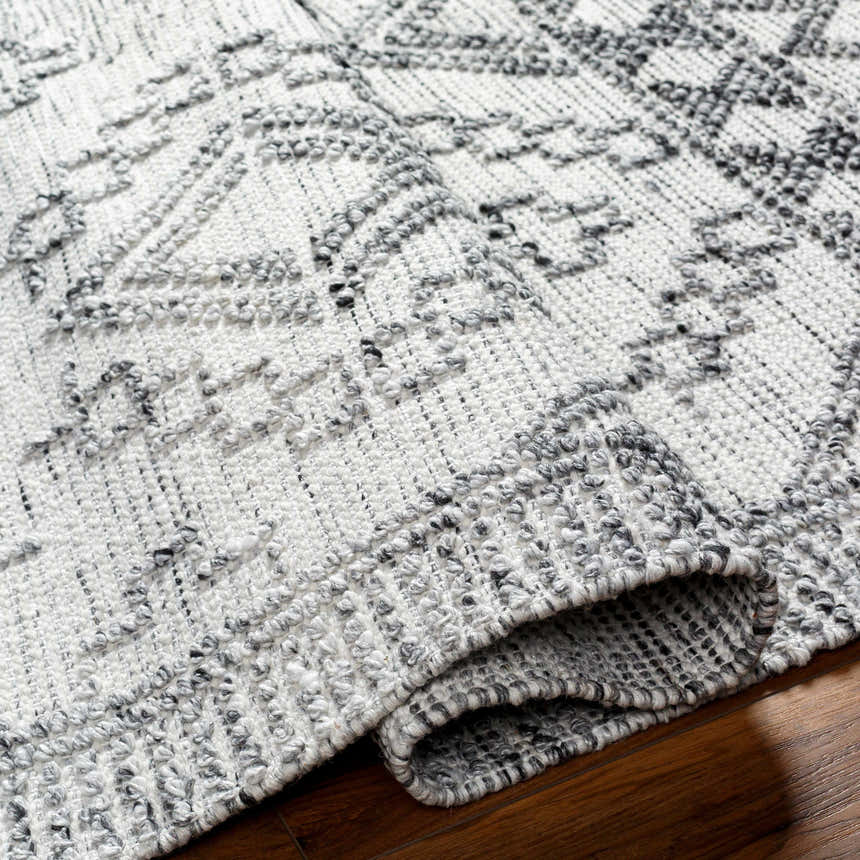Close-up of the hand woven Adan Area Rug. Arctic stone, dark gray, and nutmeg colors with a farmhouse style design. Fold
