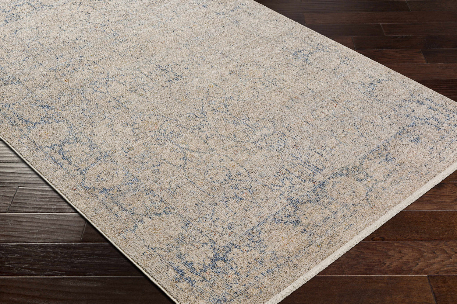 Close-up of Dian Area Rug showing ivory and dark blue vintage pattern on dark wood floor. Corner