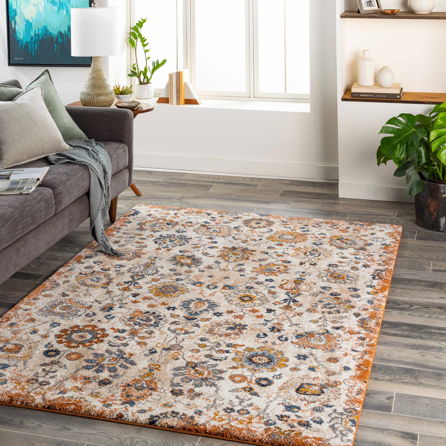 Living room scene with a Cogan Beige Thick Luxe Rug, gray sofa, wood floors, and natural light from a window. Roomscene-Rectangle