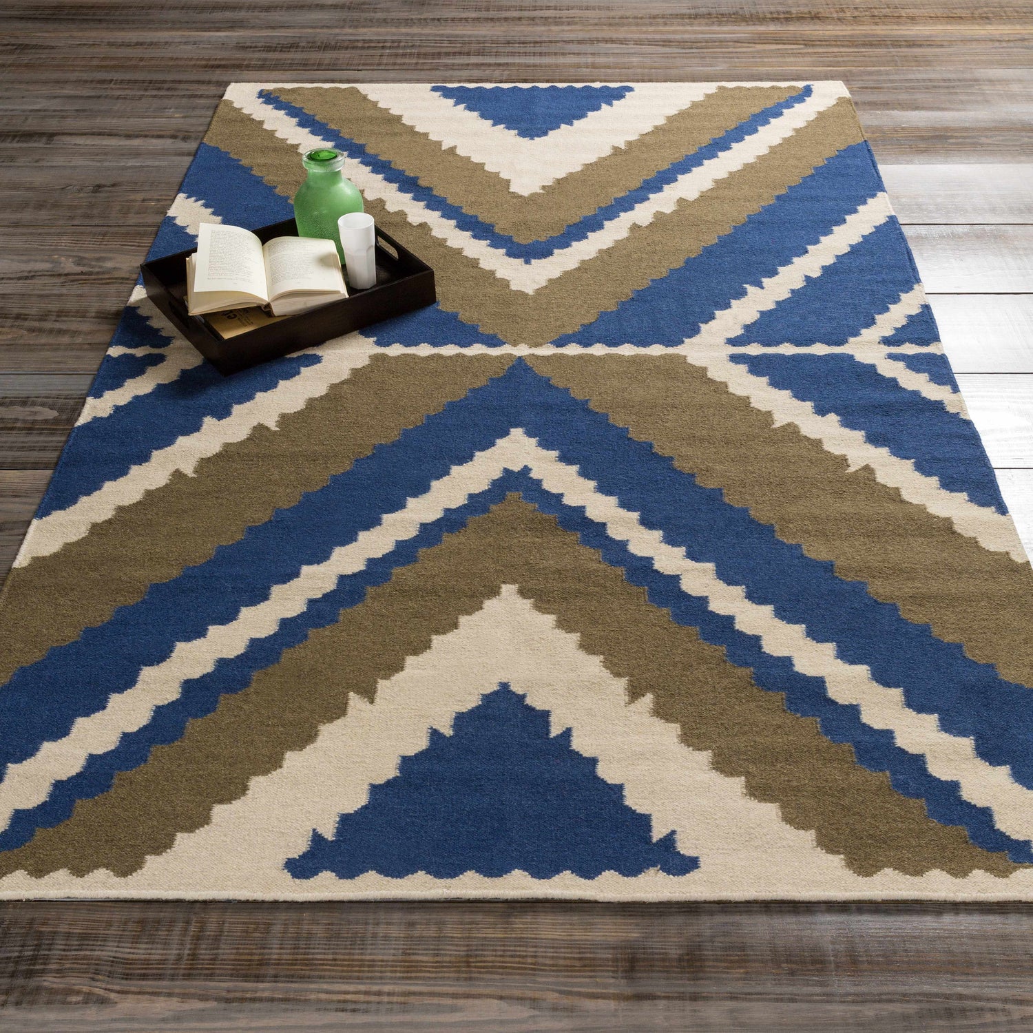 Styled Doncaster Area Rug in charcoal, dark blue, and light beige with a geometric pattern on a wood floor. Styleshot