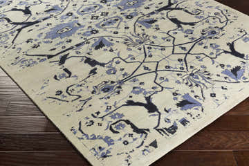 Close-up of the Doraville Area Carpet. Hand-knotted wool rug in black, blue, and seafoam with a traditional floral pattern. Corner