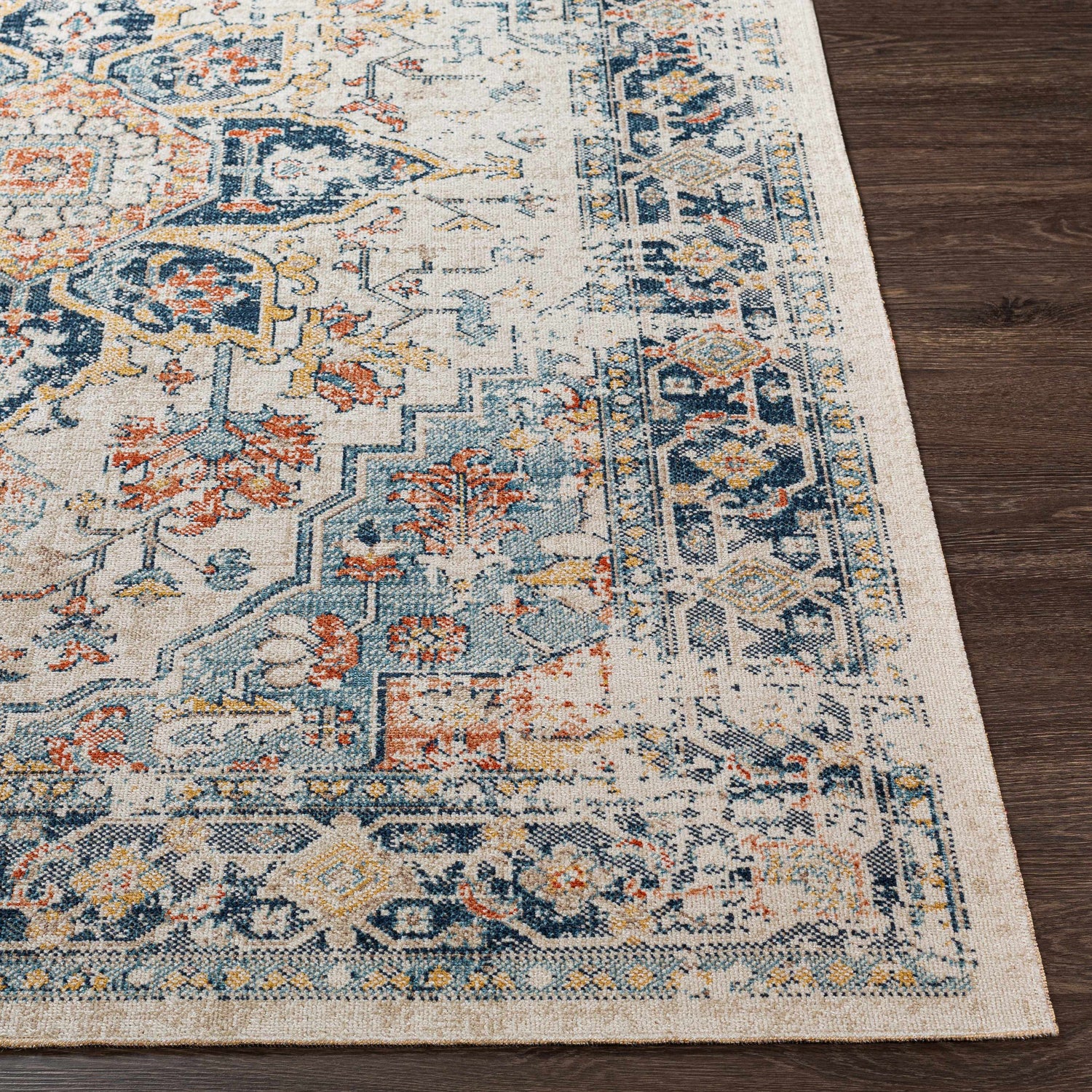 Close-up of the Dorval Traditional Rug. Cream rug with brick red, denim, and navy blue oriental pattern on dark wood floor. Front