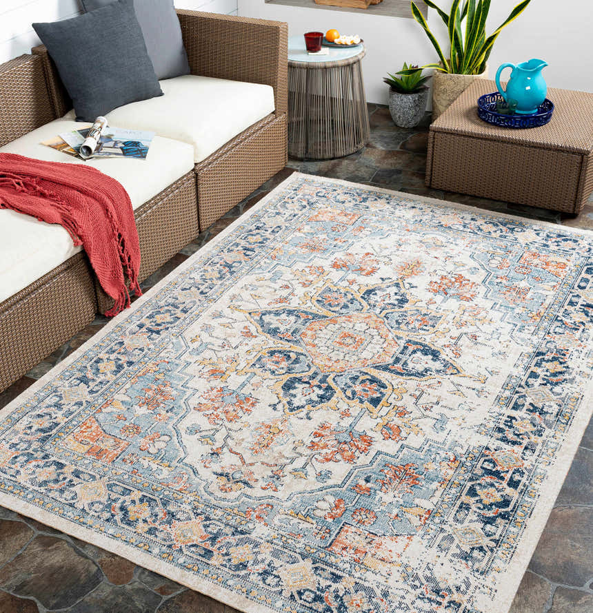 Outdoor patio scene with a Dorval Traditional Rug in brick red, cream, and denim. Wicker furniture and slate tile flooring. Roomscene-Rectangle