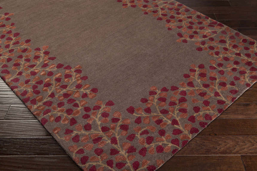 Close-up of the Dovercourt Clearance Rug. The rug is brown with a brick red and mustard leaf pattern border. Corner