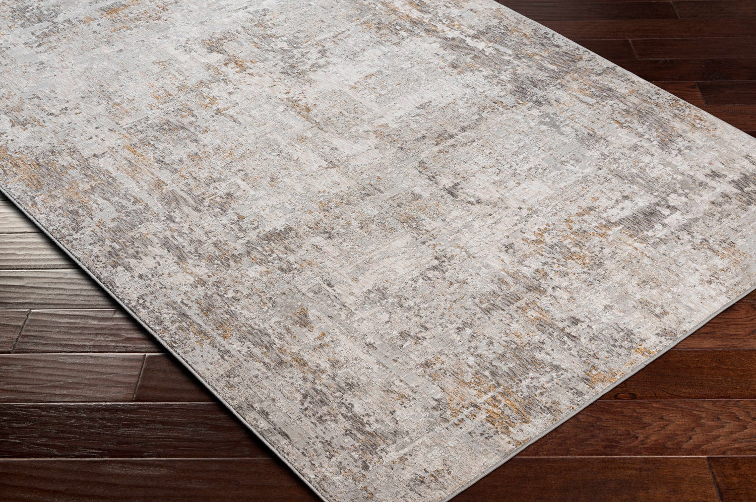 Close-up of Dowell Luxe Textured Area Rug on dark wood floor. Abstract design in gray, off-white, and mustard. Corner