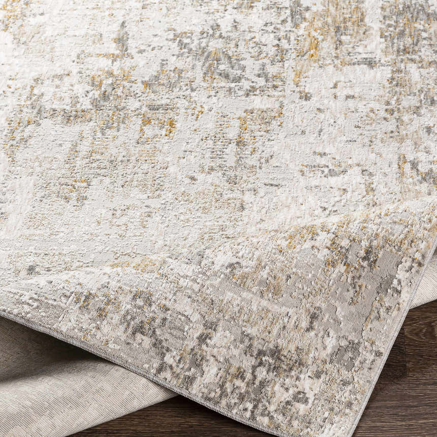 Close-up of the Dowell Luxe Textured Area Rug showing its off white, gray, and mustard abstract design and soft texture. Fold
