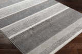 Close-up of the Dugginsville Area Rug showing gray and white stripes with a subtle herringbone pattern on dark wood floors. Corner