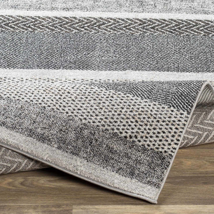 Close-up of the Dugginsville Area Rug, a contemporary rug with gray, black, and white geometric patterns. Fold