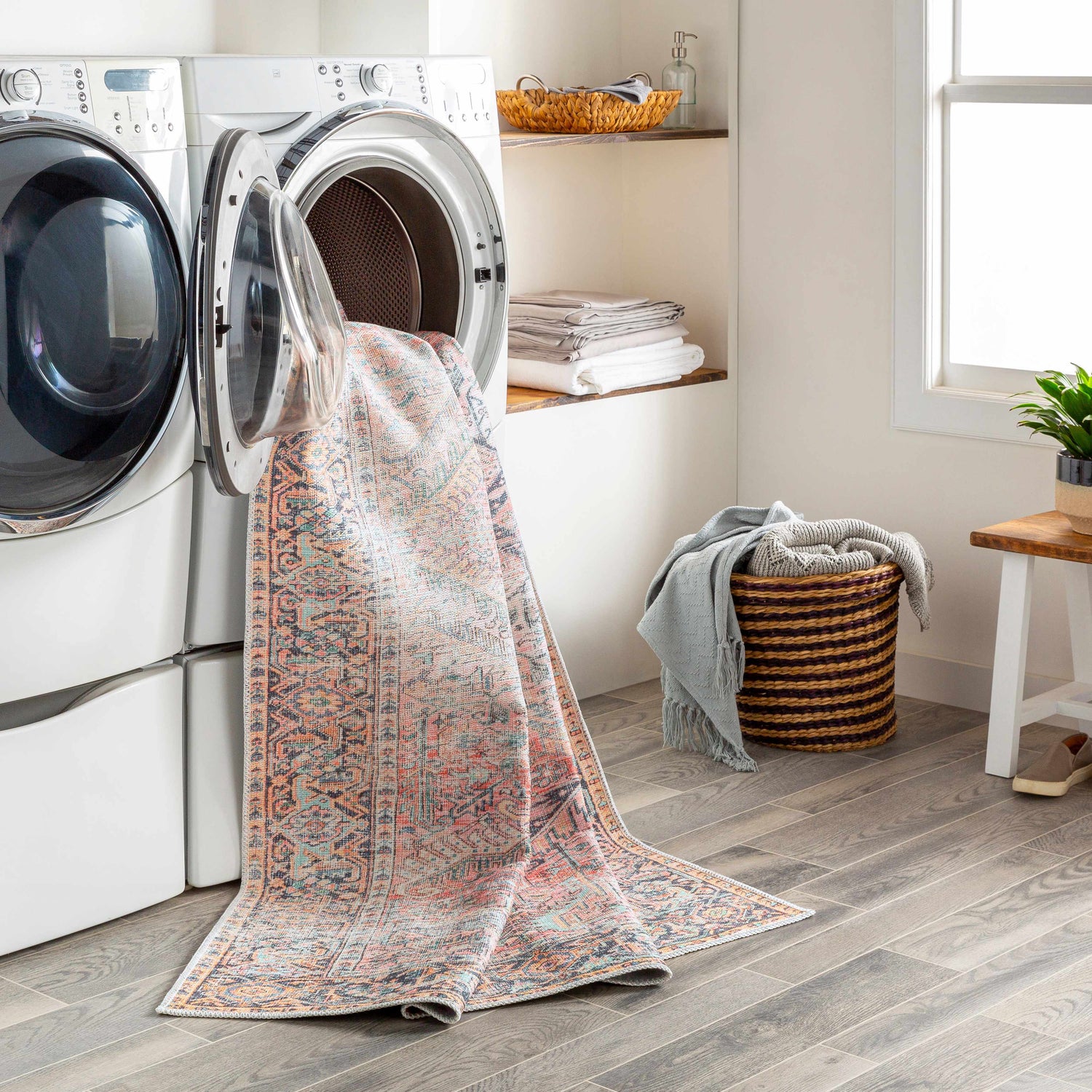 Laundry room with Dunsha Boutique Washable Area Rug spilling from the washing machine. Easy-clean rug in blue, coral, and pink. Washing-Machine