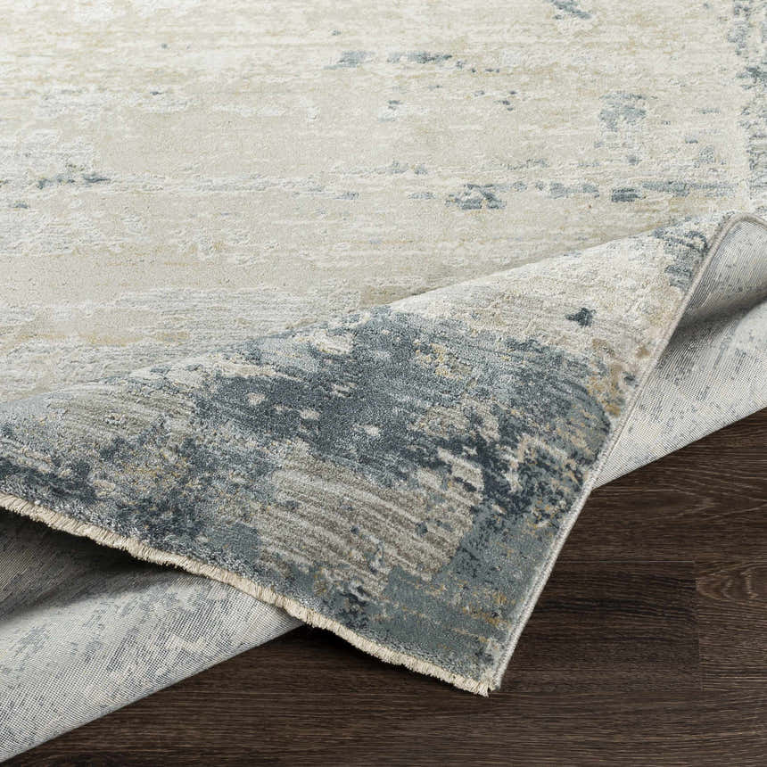 Close-up of the Devonport Thick Luxe Area Rug showing its light gray, taupe, and navy abstract pattern and texture. Fold