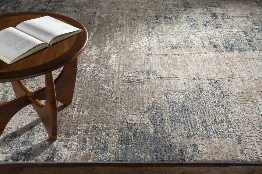 Living room scene with a Devonport area rug in dusty sage, light gray, and navy. Wood side table with open book. Styleshot