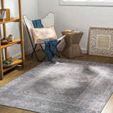 Cozy room scene with a Baltinglass Gray Washable Rug, white chair, wood accents, and a light, airy feel. Roomscene-Rectangle