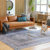Living room scene with a brown leather sofa and the Baltinglass Gray Washable Rug. Farmhouse style with light wood floors. Roomscene-Rectangle
