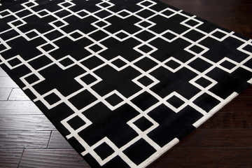 Close-up of Eaglescliffe Premium Area Carpet: black wool rug with white geometric diamond pattern on dark wood floor. Corner