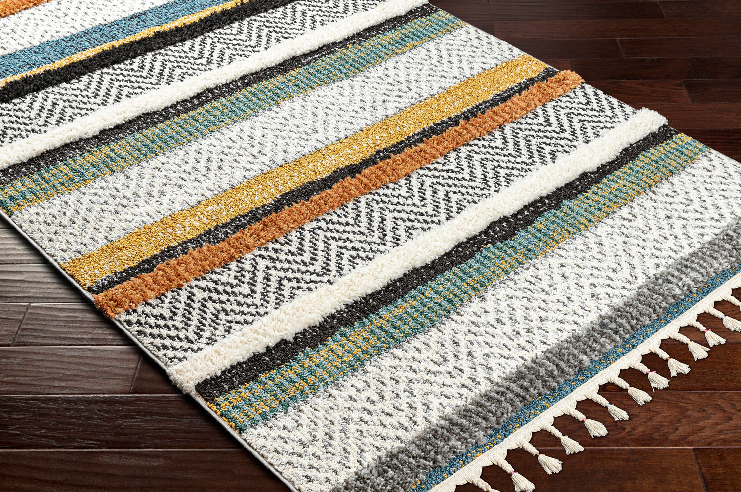 Close-up of the Edmundston Area Rug, featuring black, blue, bone, camel, and mustard stripes with a subtle herringbone pattern. Corner