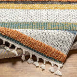 Close-up of the Edmundston Area Rug featuring black, blue, bone, and mustard stripes and decorative tassels. Fold
