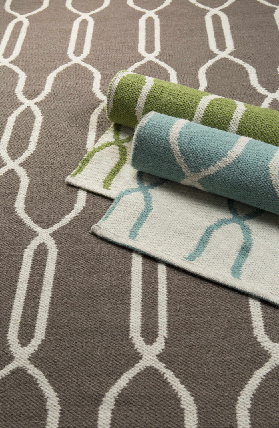 Effie Reversible Area Carpet close-up. Brown wool rug with cream geometric pattern. Rolled rugs show reversible color options. Styleshot