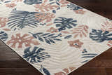 Close-up of the Ekin Area Rug showing a coastal floral pattern in charcoal, beige, gray, and nutmeg on a dark wood floor. Corner