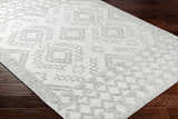 Close-up of Elin Area Rug in arctic stone and dark gray with a geometric farmhouse pattern on dark wood floors. Corner