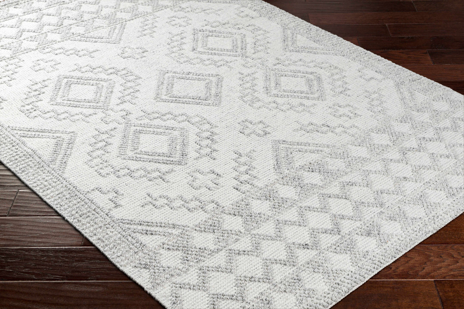 Close-up of Elin Area Rug in arctic stone and dark gray with a geometric farmhouse pattern on dark wood floors. Corner