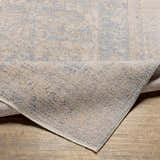 Close-up of the Tusa Blue Area Rug showing its traditional pattern, light blue, ivory, and gray colors, and soft texture. Fold