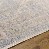 Close-up of the Tusa Blue Area Rug showing its ivory, blue, and gold traditional pattern and textured, machine-woven construction. Texture