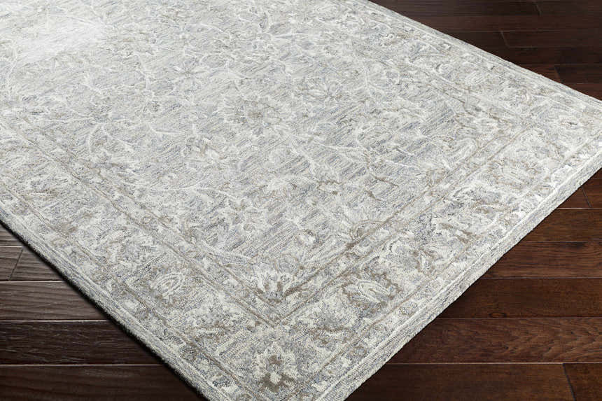 Close-up of the Eriline Wool & Faux Silk Rug in denim, ivory, sage, and taupe on dark wood floor. Traditional floral pattern. Corner