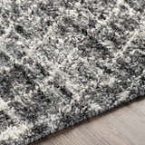 Close-up of the Erina Premium Rug, showing its black, charcoal, cream, and gray textured, hand-knotted design. Texture
