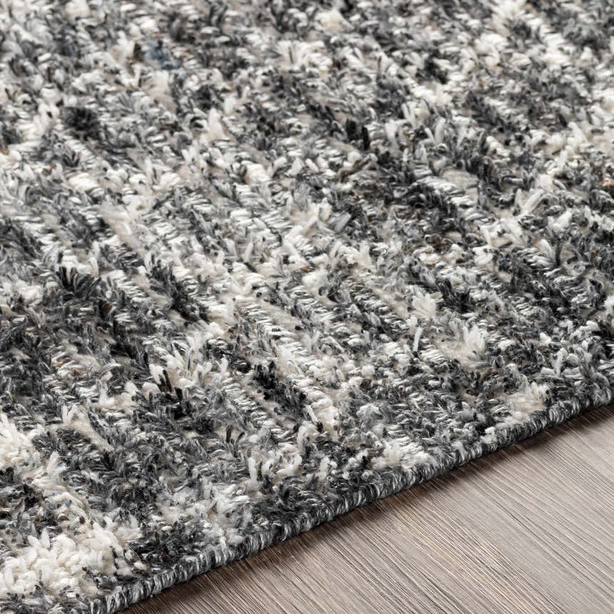 Close-up of the Erina Premium Rug, showing its black, charcoal, cream, and gray textured, hand-knotted design. Texture