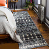 Bedroom scene with Erina Premium Rug in black, charcoal, and cream. Bohemian rug runner on hardwood floor by bed and vintage radiator. Roomscene-Runner