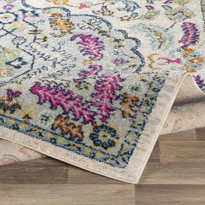 Close-up of Errol Area Rug showing its aqua, burnt orange, pink, and blue bohemian floral pattern and soft texture. Fold