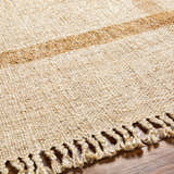 Close-up of the hand-woven Errin Jute Area Rug. Beige and camel tones with jute tassels. Farmhouse style. Texture