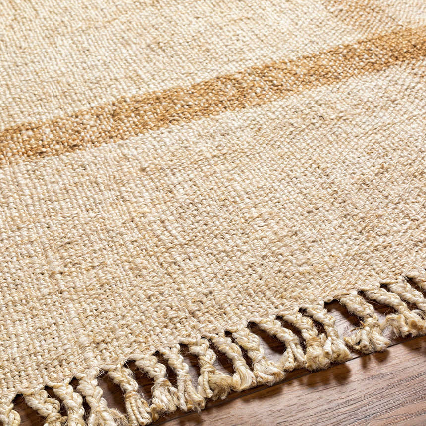 Close-up of the hand-woven Errin Jute Area Rug. Beige and camel tones with jute tassels. Farmhouse style. Texture