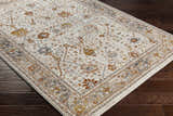 Close up of Paatan Luxe Floral Oushaq Area Rug. Cream rug with traditional floral pattern in gold, brown, and gray on dark wood floor. Corner