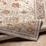Close-up of the Paatan Luxe Floral Oushaq Area Rug featuring a traditional floral pattern in cream, rust, and gray tones. Fold