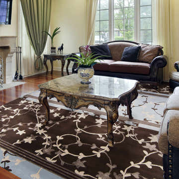 Living room scene with a brown Everly Area Rug featuring a floral pattern under a marble-top coffee table. Roomscene-Rectangle