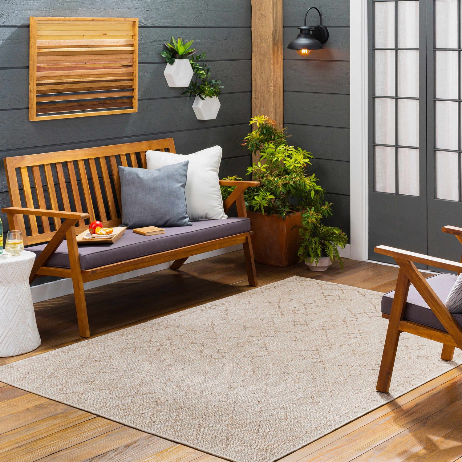 Cozy outdoor patio scene with a Maunawili Cream Nordic Rug, wood bench with cushions, and potted plants. Roomscene-Rectangle