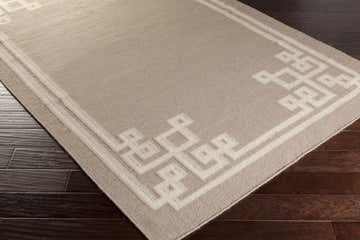 Close-up of the Fagus Area Rug. Hand-woven wool rug in gray and light beige with a geometric border pattern. Corner