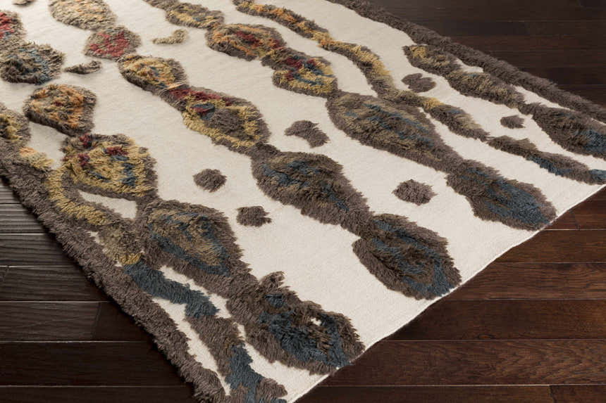 Close-up of the Brown Mustard Nila Carpet showing its shag texture and geometric pattern in brown, beige, and navy. Corner