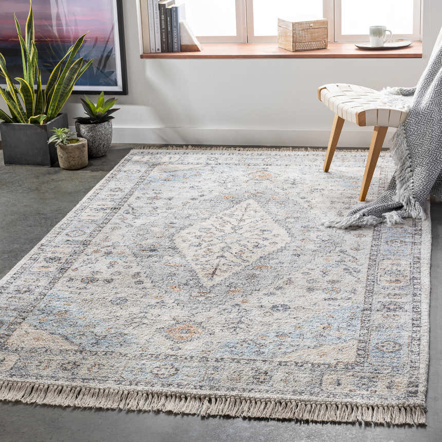 Light-filled room with Fernhurst Distressed Beige Viscose&Cotton Rug, woven chair, plants, and neutral decor. Roomscene-Rectangle
