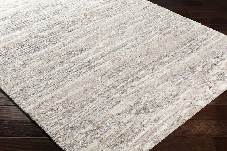 Close-up of the Ferrelview Area Rug, a contemporary design in gray, ivory, and tan on dark wood flooring. Corner