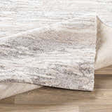 Close-up of the Ferrelview Area Rug showing a textured, abstract pattern in gray, ivory, and tan on a wood floor. Fold