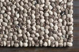 Close-up of hand woven Fillmore Area Carpet showing wool texture and pebble design in black, charcoal, cream, and gray. Swatch