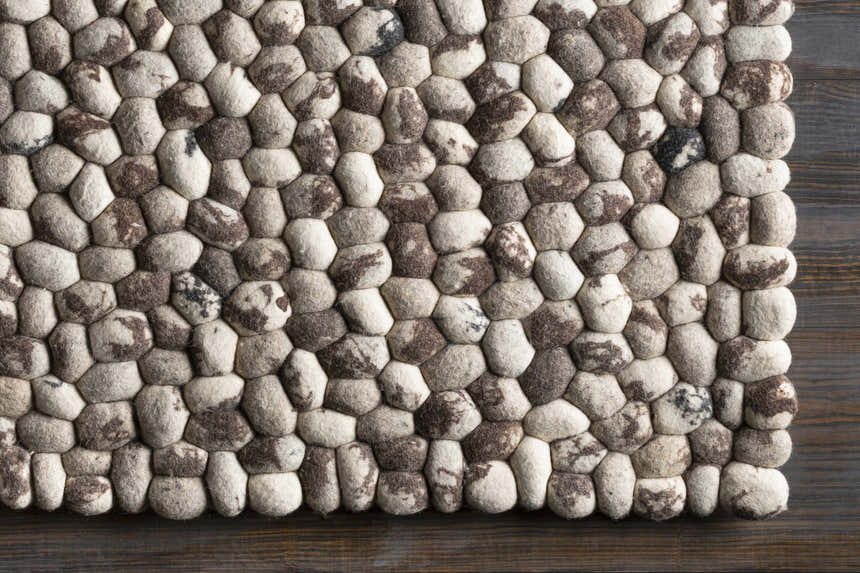 Close-up of hand woven Fillmore Area Carpet showing wool texture and pebble design in black, charcoal, cream, and gray. Swatch