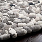 Close up of a hand woven Fillmore Area Carpet. Wool rug with black, charcoal, cream, and gray pebble-like design. Pile