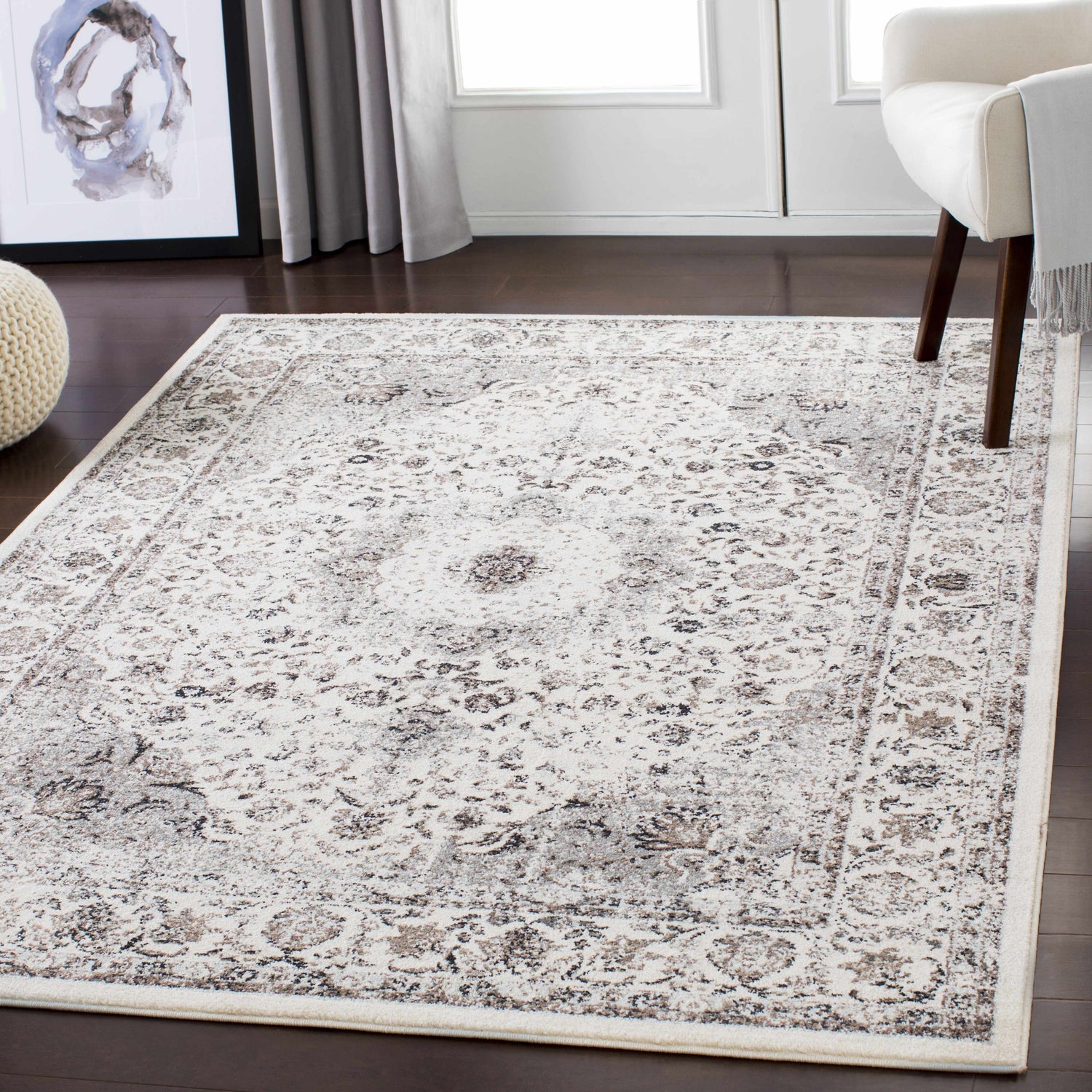 Living room scene with a Finksburg Area Rug in camel, charcoal, and ivory under a modern chair on dark wood floors. Roomscene-Rectangle