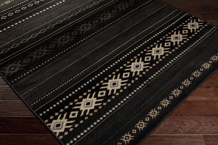 Close-up of the Fogertown Black Western Rug. Features a black base with beige, gray, and tan Southwestern-inspired geometric patterns. Corner