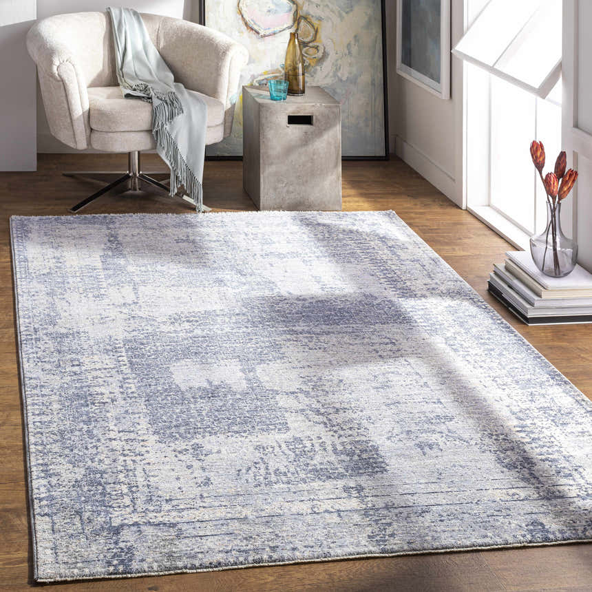 Living room scene with a blue Foley Carved Statement Rug, beige chair, concrete side table, and wood floors. Roomscene-Rectangle