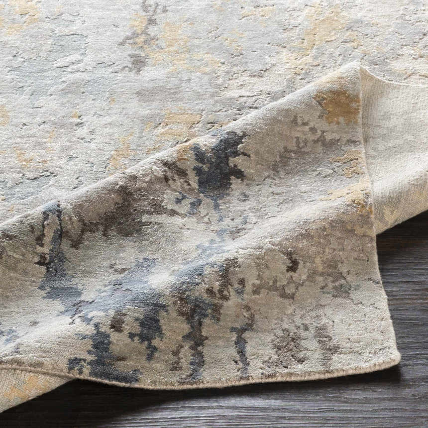 Close-up of the Follansbee Area Rug, showcasing its beige, charcoal, and gray contemporary design and hand-knotted texture. Fold