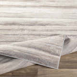 Close-up of the Fombell Abstract Striped Area Rug. Features charcoal, gray, tan, and white tones with a subtle striped pattern. Fold